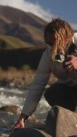 een Mens verzamelt water in een fles van een berg rivier. wandelen in de bergen, een reiziger blust zijn dorst in de bergen. video