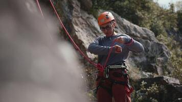 focalizzata scalatore preparazione Ingranaggio per salita, sicurezza controlli contro roccioso terreno sfondo enfatizzare importanza di preparazione. video