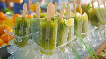 An outdoor market stall selling homemade popsicles in eclectic flavors like mojito green tea and coconut lerass video