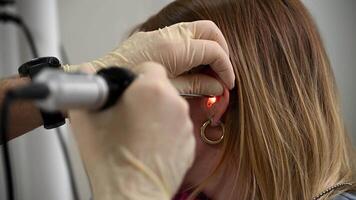 otolaryngologist conducts medical examination of ear with otoscope closeup video
