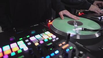 DJs play records at the disco. Art. Close-up of DJ's hand on the mixer. Glowing music panel at a party. The work of musicians in a nightclub video