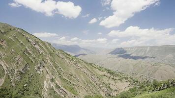 Bird's-eye view. Action. Beautiful summer view of the mountains with green vegetation over a bright blue light sky. video