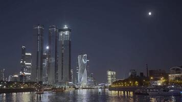 Moscow 2021. Action. Beautiful huge evening buildings near the river in Moscow were shot from afar on a dark evening with bright lights and lanterns that glow . video