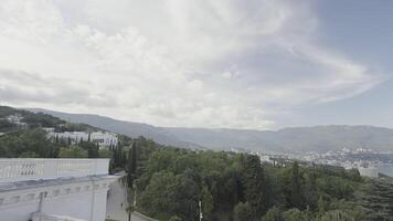 Beautiful summer park over the sea. Action. Huge long mountains and the sea, and a summer forest is visible above it, a cloudy sky. video