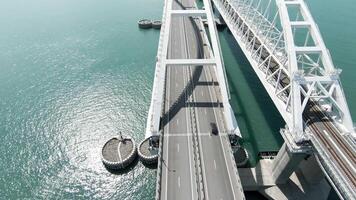 Flight above new white bridge with moving vehicles. Action. Breathtaking marine landscape with a long bridge above blue calm water. video