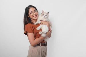 Portrait of young Asian woman in brown shirt holding her ragdoll cat and smiling to the camera isolated over white background. photo