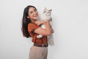 Portrait of young Asian woman in brown shirt holding her ragdoll cat and smiling to the camera isolated over white background. photo