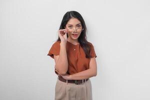 Stylish Asian woman in brown shirt wearing eyeglasses doing a chic and elegant pose isolated by white background. photo