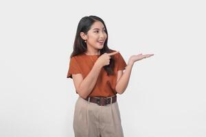 Happy Asian woman is smiling and pointing to the copy space beside her over isolated white background. photo