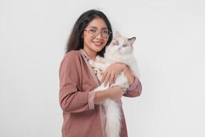 Lovely Asian woman wearing eyeglasses holding her ragdoll cat and smiling to the camera isolated over white background. photo