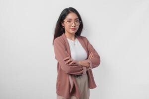 Smiling young Asian woman wearing eyeglasses standing with arms folded with confident expression isolated over white background. photo