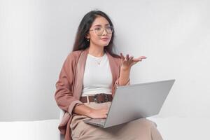 Serious young Asian business woman sitting down with a laptop while having discussion meeting, isolated by white background. photo