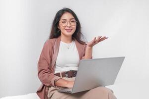 Serious young Asian business woman sitting down with a laptop while having discussion meeting, isolated by white background. photo