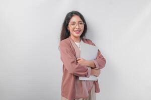 Attractive young Asian business woman holding a laptop close while smiling happily over isolated white background. photo