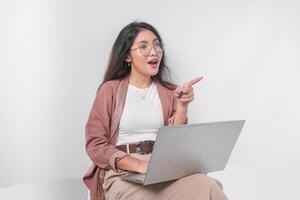 hermosa joven asiático negocio mujer sentado abajo con un ordenador portátil haciendo entrevista, aislado por blanco antecedentes. foto