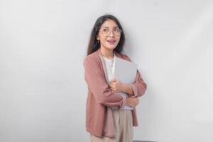 Attractive young Asian business woman holding a laptop close while smiling happily over isolated white background. photo