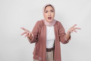 Thoughtful young Asian Muslim woman in hijab is looking confused, isolated by a white background. photo