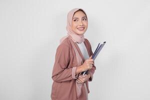 elegante asiático mujer vistiendo hijab participación documento sonriente felizmente aislado por blanco antecedentes. foto