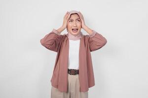 A sad Asian Muslim woman wearing hijab looking stressed and depressed or having headache, isolated white background. photo