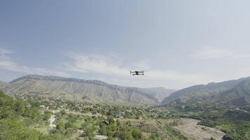 A drone flying over the mountains. Action. Beautiful daytime summer landscape with mountains and blue sky overhead, also with residential buildings and green trees. video