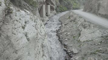 A powerful stream of water is squeezed between the sides of the rocks. Action. Aerial view of the river flowing in a gorge between mountains. video