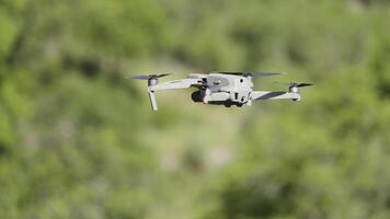 A drone flying over nature.Action. A small device for taking photos from a height in nature that shoots videos and spins in front of beautiful mountains in daylight.