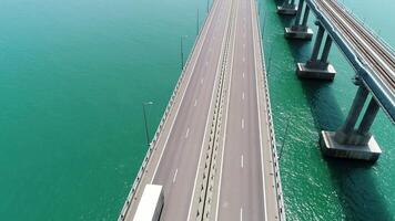 Flight above new white bridge with moving vehicles. Action. Breathtaking marine landscape with a long bridge above blue calm water. video