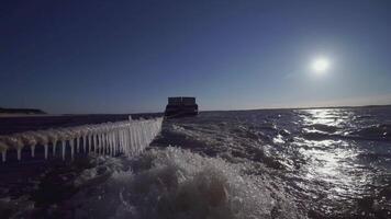 groß Lastkahn beim das Norden Pole. Clip. im das Vordergrund Seil mit Eiszapfen. im das Hintergrund, ein schwer Lastkahn im Eis Wasser ist im Fokus. ein Schiff ziehen ein Lastkahn im Abschleppen video