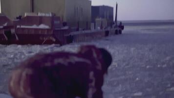 Large barge at the North Pole. CLIP. In the foreground is a man in defocus. In the background, in focus, a heavy barge in the water with ice video