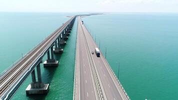 Aerial view of a bridge over the sea with calm water. Action. Long straight bridge with the moving vehicles above beautiful sea. video