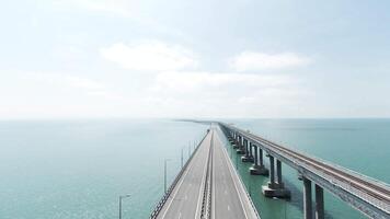 Top view of long bridge highway across sea. Action. Beautiful landscape with hinged white bridge over turquoise sea. Bridge with highway across sea on sunny day video