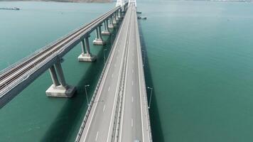 aéreo Visão do uma ponte sobre a mar com calma água. Ação. grandes em linha reta ponte com a comovente veículos acima lindo mar. video