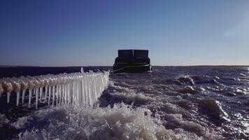 groß Lastkahn beim das Norden Pole. Clip. im das Vordergrund Seil mit Eiszapfen. im das Hintergrund, ein schwer Lastkahn im Eis Wasser ist im Fokus. ein Schiff ziehen ein Lastkahn im Abschleppen video