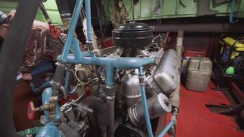 Engine of a small ship in the engine room. CLIP. An engine room with an engine to which blue pipes connected with people in the background video