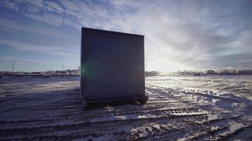 The loading container is on the snow. CLIP. View from different sides of one container standing on the ground. Blue sky and snow behind the container video