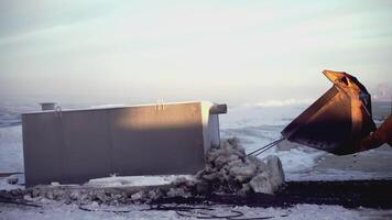 Big tractor at the north pole. CLIP. In the foreground, a tractor is pulling a heavy load. In the , people walk and tractors work on an icy space video