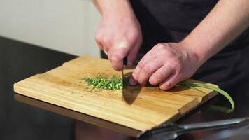 el cocinar cortes el cebolla. Arte. hombre en el cocina cortes blanco cebolla dentro medio anillos con cuchillo. siguiente a el tablero es espátula y bolso de Romero video