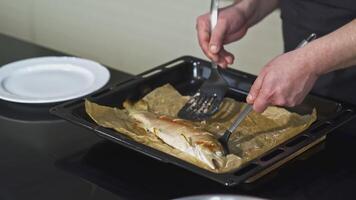 Russie, Moscou - Mars 17, 2022. cuisinier met le poisson sur une plaque. art. une homme porte une poisson sur une plat avec deux mains. cuit poisson cuit dans le four. le cuisinier sert une plat de poisson pour portion dans le video