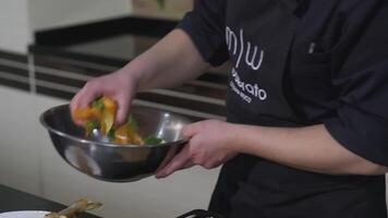 Ekaterimburgo, Rusia - febrero 25, 2022. el cocinar pone el ensalada en un plato con pez. Arte. servicio un pescado plato. el cocinar pone el ensalada desde un metal cuenco dentro el principal plato video