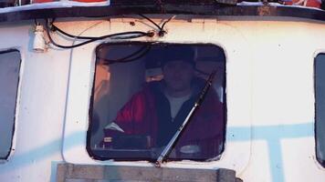 MOSCOW, RUSSIA - FEBRUARY 25, 2022 . The man in the window on the ship. CLIP. Close-up on the porthole in which the captain of the ship is standing. Behind the windshield on the captain's bridge is a video