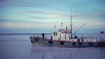 groß Lastkahn beim das Norden Pole. Clip. im das Vordergrund Seil mit Eiszapfen. im das Hintergrund, ein schwer Lastkahn im Eis Wasser ist im Fokus. ein Schiff ziehen ein Lastkahn im Abschleppen video