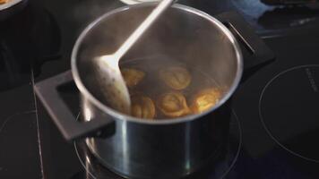 Dumplings in the broth are mixed with slotted spoon. ART. Dumplings are cooked in pot on the stove. With a ladle they caught one dumpling from the pan video