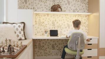 Interior of children's room with boy sitting at table. Creative. Boy is studying at desk. Children's room of smart boy studying at table video