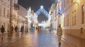 Winter Street. Action.A beautifully decorated New Year's Eve evening street that burns with lights and along which people walk. video