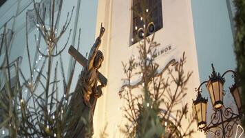 A beautiful small monument with burning garlands around. Action. A white building with branches from fir trees next to which there are glowing lanterns and everything is decorated with Christmas video