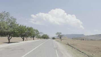 premier la personne vue de Suivant le rural route sur nuageux bleu ciel Contexte. action. été paysage avec vert champ et croissance des arbres. video