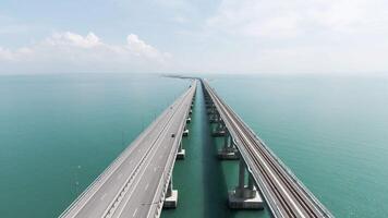 Antenne Aussicht entlang das lange schön Brücke über Türkis Meer. Aktion. fliegend über Biegen Brücke mit Fahren Autos. video