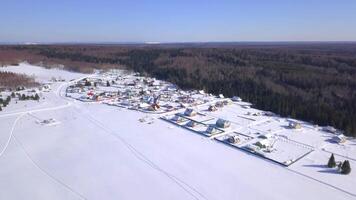 ojo de pájaro vista. acortar. invierno bosque cerca el pueblo y bosque y campos y azul cielo video