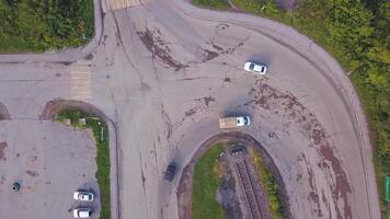 View from a helicopter . Clip. View of a curving road with cars next to a green park and some kind of base with parking video