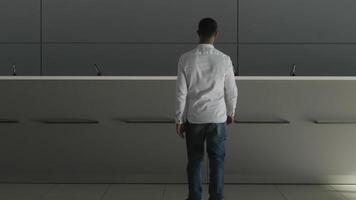 minimaliste intérieur de une Hôtel hall avec le accueil bureau. hdr. arrière vue de une homme d'affaire dans blanc chemise Aller à le réceptionniste et demander quelque chose. video